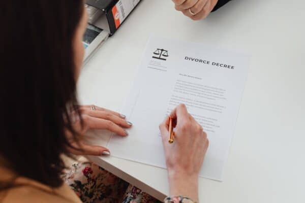 a-person-signing-a-divorce-decree-document-with-focus-on-hands-and-paper - Granholm & Gynac, LLC a-person-signing-a-divorce-decree-document-with-focus-on-hands-and-paper